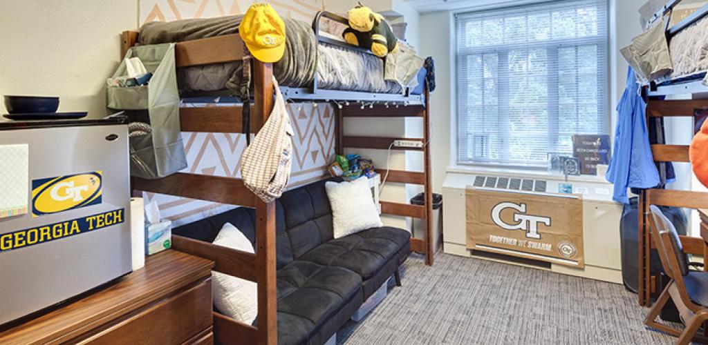 Bedroom with bunk beds. One with a sofa underneath, another one with a desk.